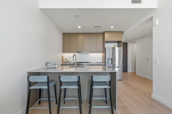 a kitchen with kitchen island wooden cabinets and refrigerator