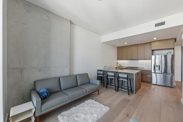 a living room with stainless steel appliances furniture and a kitchen view
