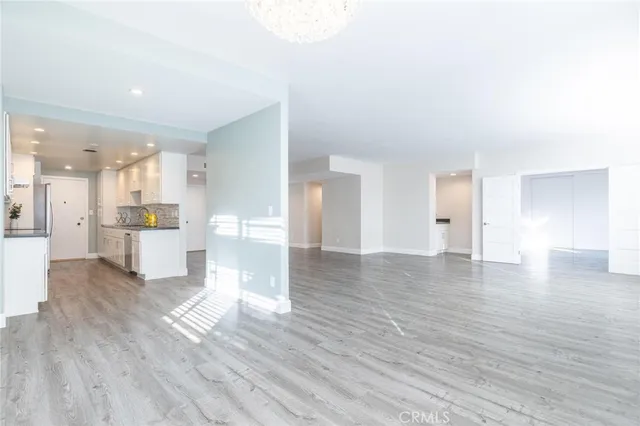 a view of a kitchen and an empty room with wooden floor