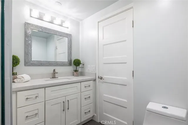 a bathroom with a double vanity sink and mirror with toilet