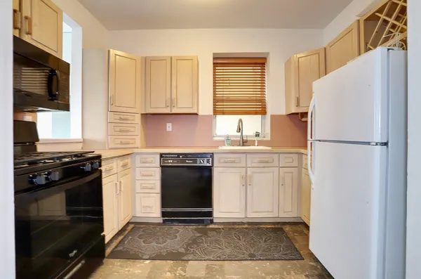 a kitchen with granite countertop a refrigerator stove and cabinets