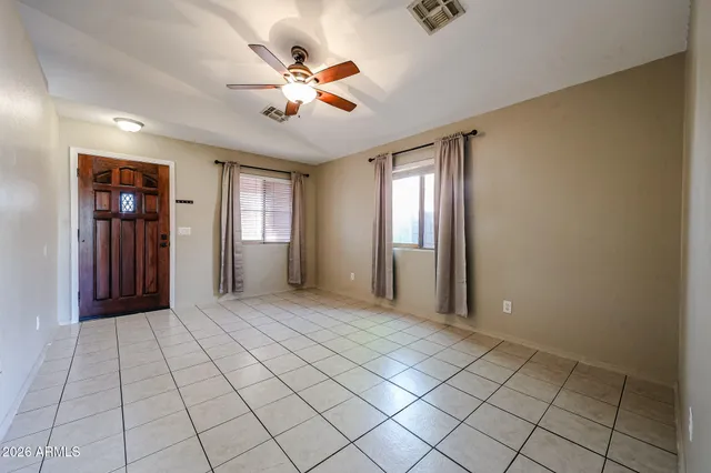 a view of an empty room with window and chandelier fan
