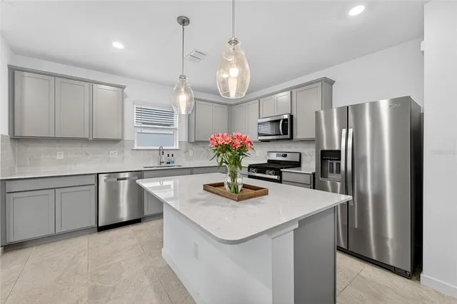 a kitchen with stainless steel appliances granite countertop a sink a refrigerator a stove a washer and dryer