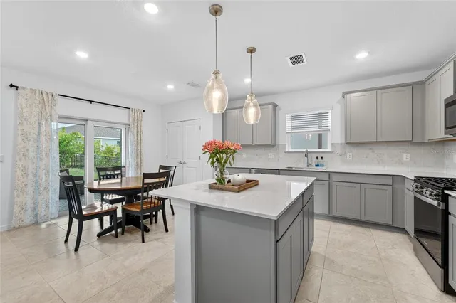a kitchen with kitchen island granite countertop a table chairs sink and cabinets