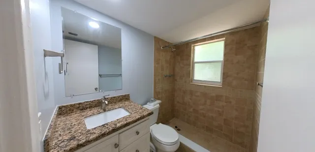 a bathroom with a granite countertop sink toilet and mirror
