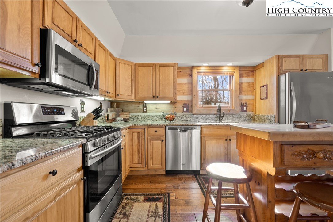 713 River Ridge Road Boone, NC 28607 - Photo 12 of 44 a kitchen with stainless steel appliances granite countertop a stove a sink dishwasher a microwave oven and a refrigerator with wooden cabinets