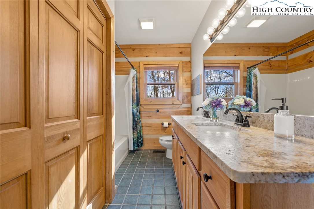 713 River Ridge Road Boone, NC 28607 - Photo 16 of 44 a bathroom with a granite countertop sink a mirror and a shower