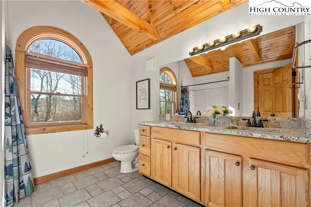 a bathroom with a granite countertop toilet a mirror a sink and a window