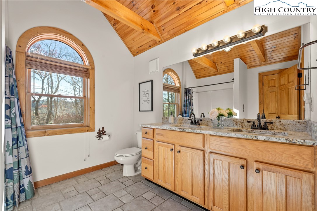 713 River Ridge Road Boone, NC 28607 - Photo 24 of 44 a bathroom with a granite countertop toilet a mirror a sink and a window