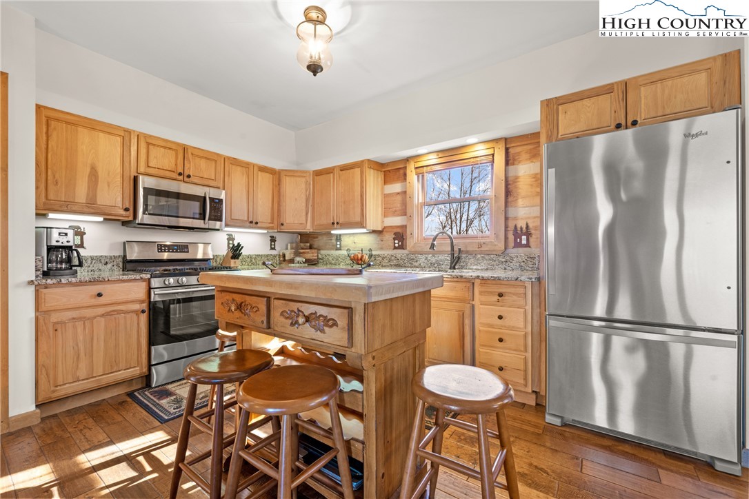 713 River Ridge Road Boone, NC 28607 - Photo 10 of 44 a kitchen with stainless steel appliances granite countertop a refrigerator a stove a sink a dining table and chairs with wooden floor
