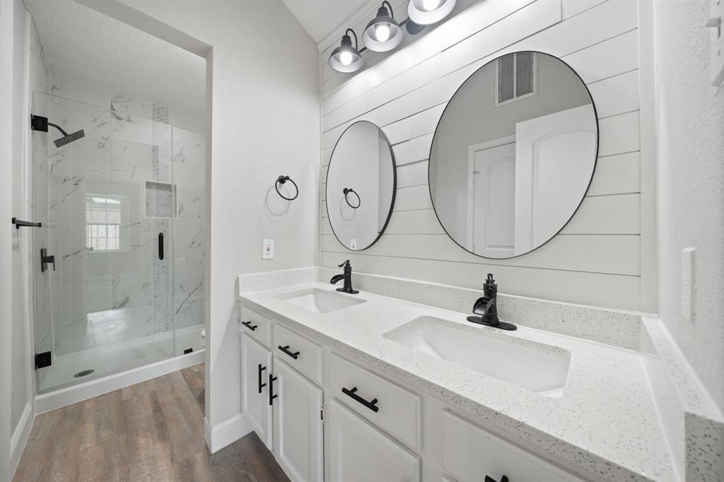 310 Valley Spring Drive Arlington, TX 76018 - Photo 15 of 24 Bathroom featuring a dual vanity with white cabinetry, light-toned countertops, and two circular mirrors