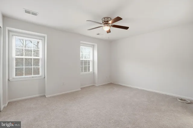 an empty room with windows and fan
