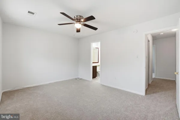 an empty room with chandelier fan and windows