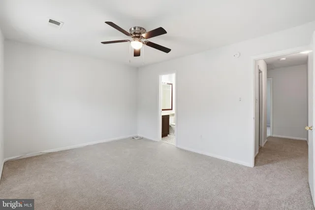 an empty room with chandelier fan and windows