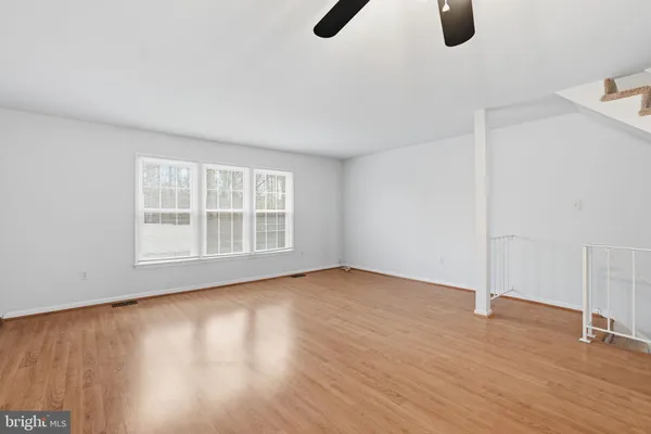 a view of an empty room with wooden floor and windows