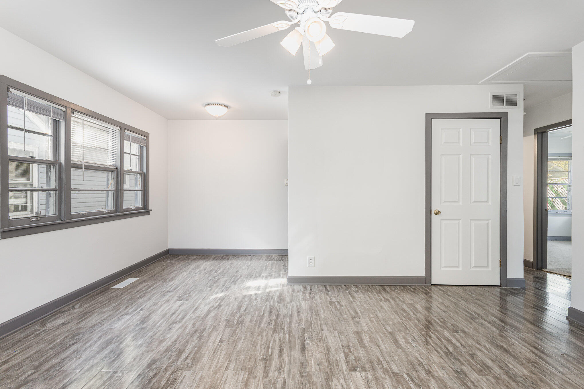 7536 Harrison Avenue Hammond, IN 46324 - Photo 7 of 16 an empty room with wooden floor chandelier fan and windows