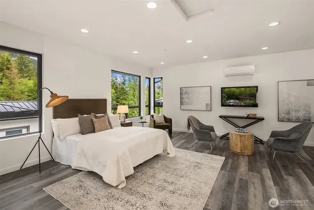 a bedroom with a bed a large window and wooden floor