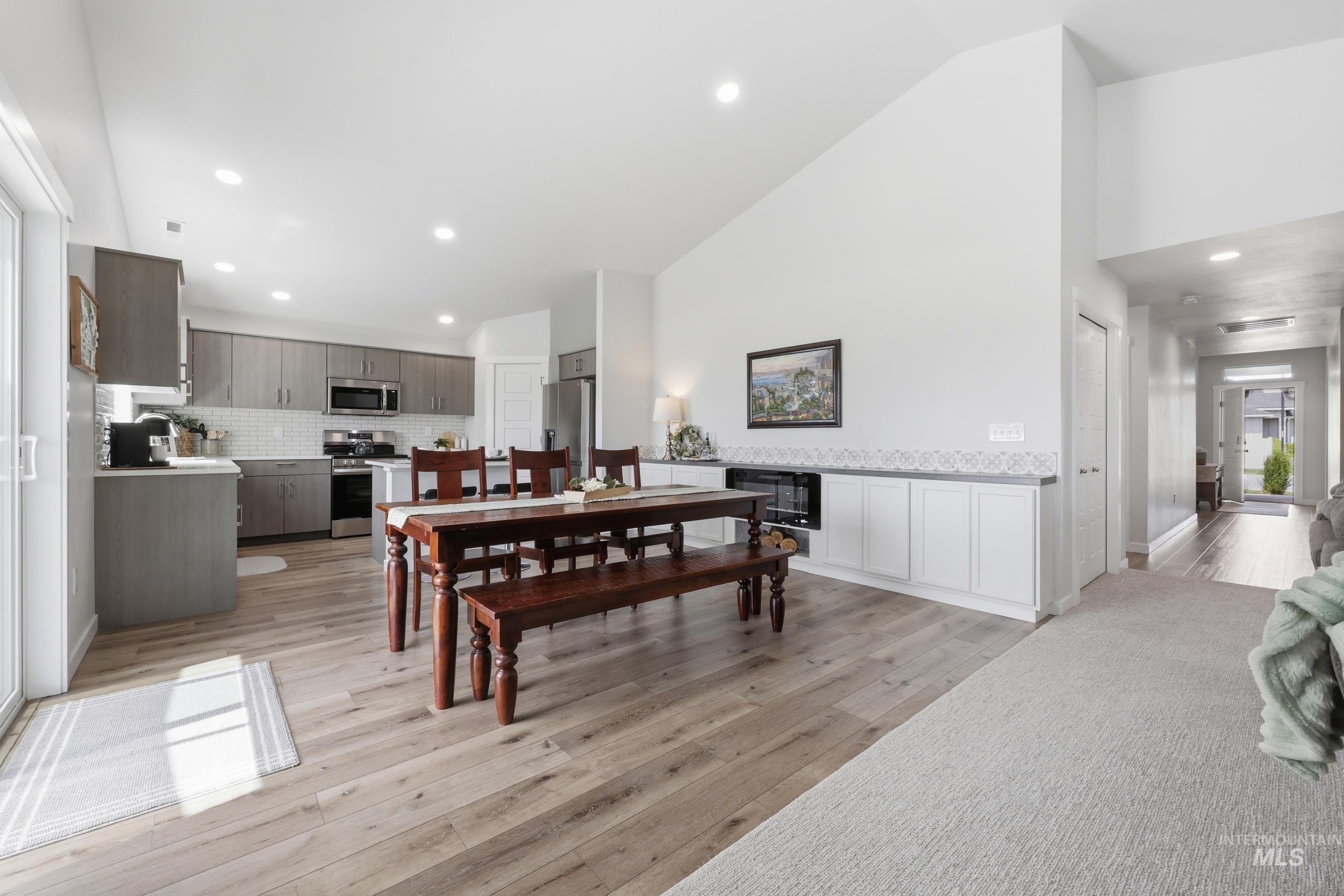 3665 W Lane Meridian, ID 83642 - Photo 11 of 42 Open-concept living area featuring wood-finish flooring, a contemporary electric fireplace with built-in cabinetry, and sliding glass doors opening to an outdoor patio with a wooden pergola