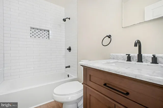 a bathroom with a granite countertop sink a toilet a mirror and shower