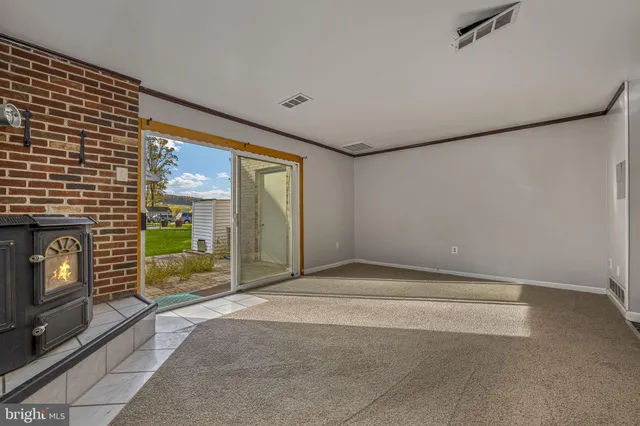 a view of an empty room with floor to ceiling window and fire place