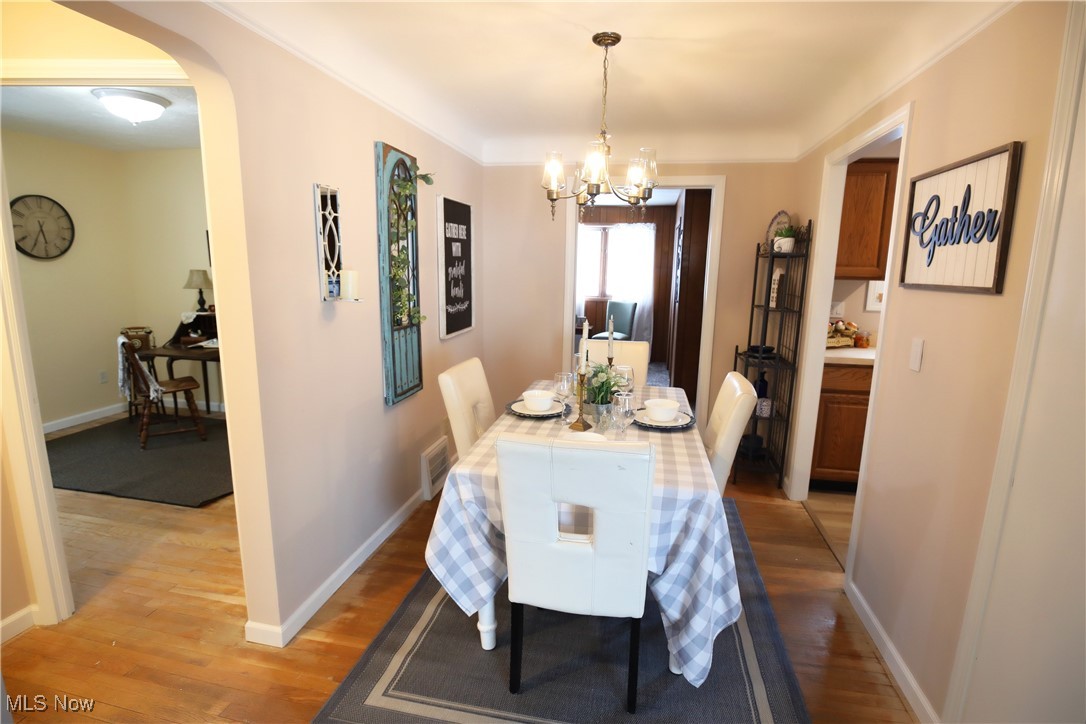1344 Lander Road Cleveland, OH 44124 - Photo 6 of 49 Dining space with arched walkways, light wood finished floors, and a chandelier