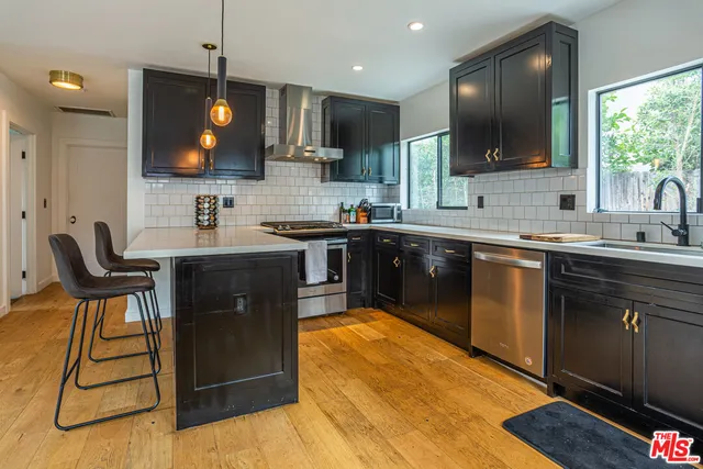 a kitchen with stainless steel appliances a sink a stove top oven a counter space and cabinets