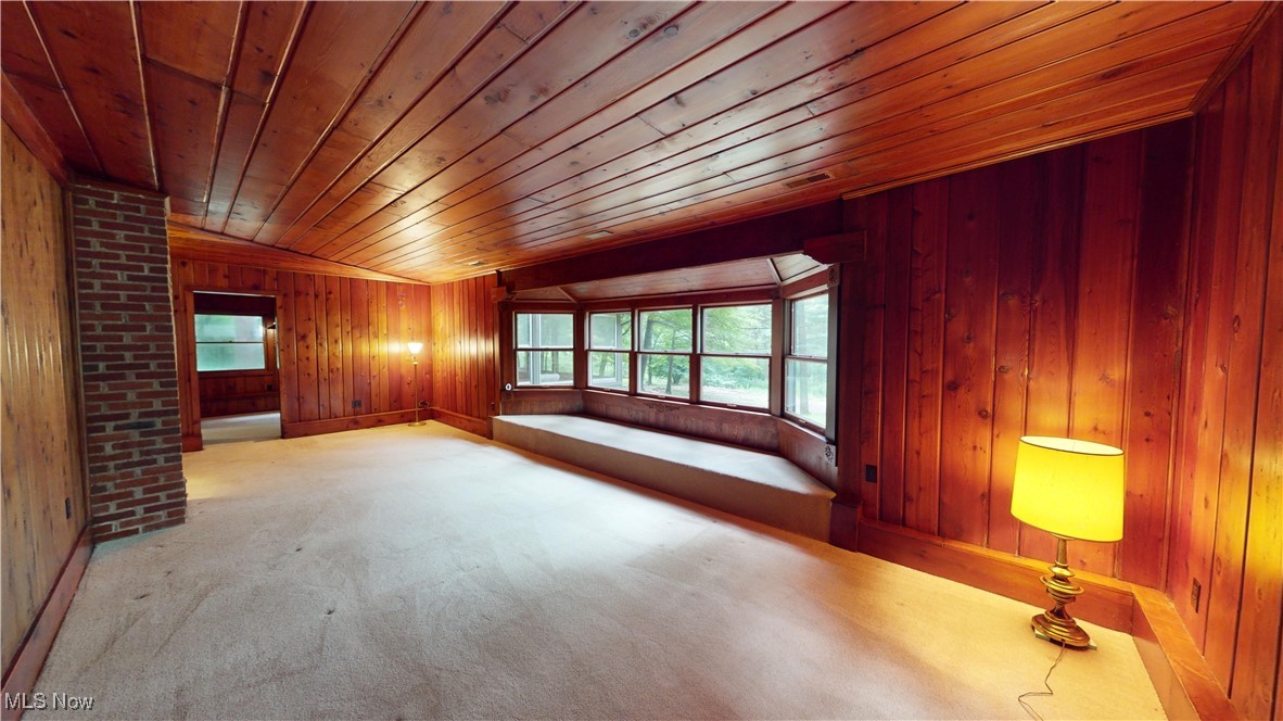 13696 Sperry Road Novelty, OH 44072 - Photo 18 of 40 Spare room featuring wooden walls, brick wall, carpet floors, vaulted ceiling, and wood ceiling