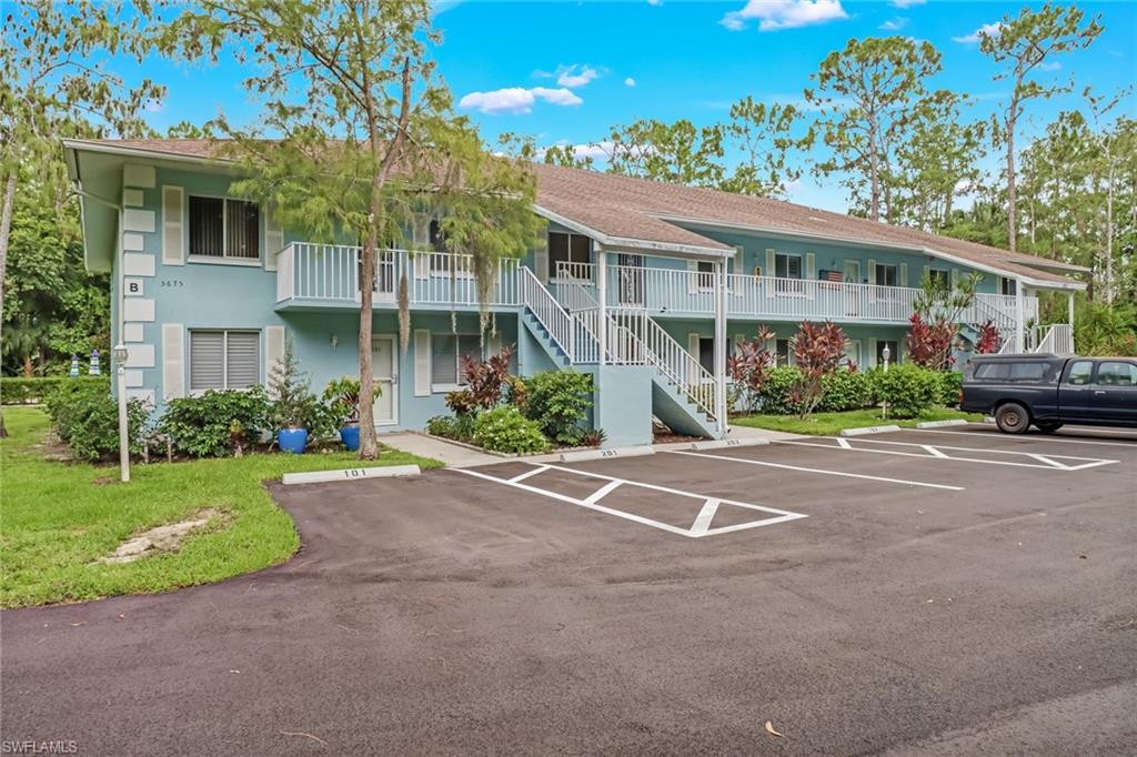 5675 Whitaker Road, Unit B202 Naples, FL 34112 - Photo 2 of 26 a front view of a house with a yard and potted plants