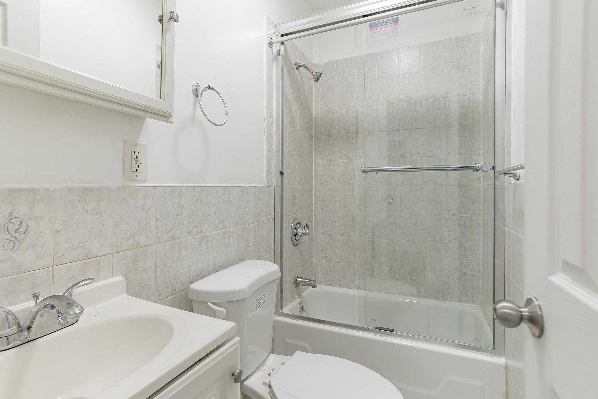 2263 Ryer Avenue Bronx, NY 10457 - Photo 14 of 49 Full bath with bath / shower combo with glass door, vanity, tile walls, and wainscoting