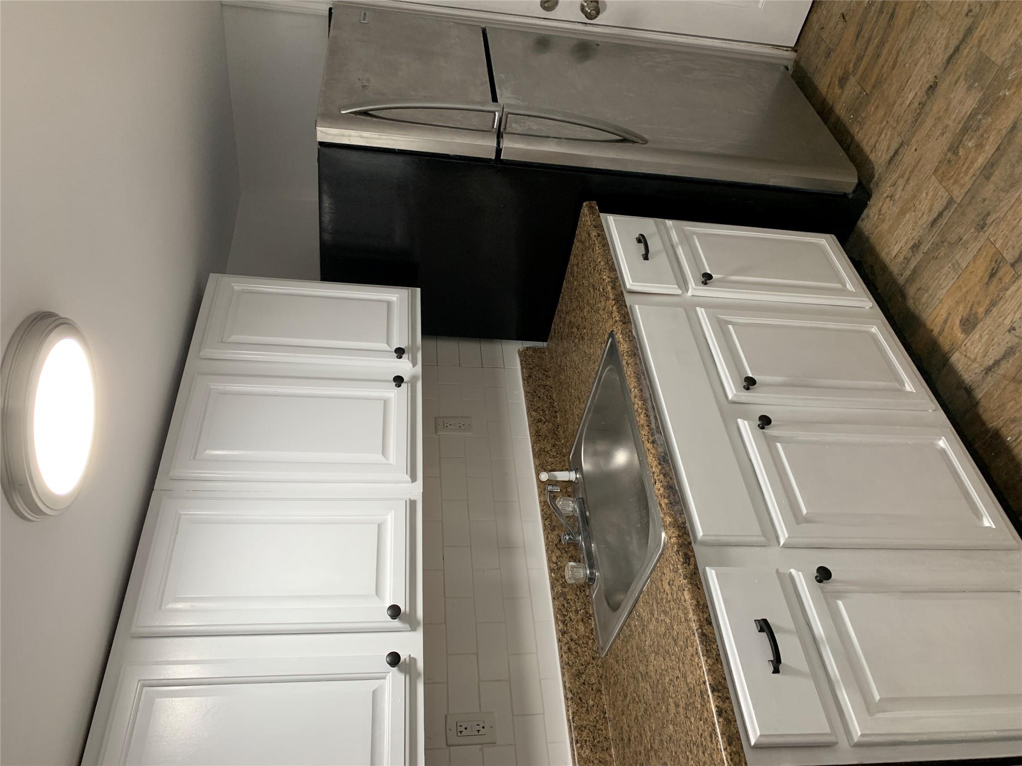2263 Ryer Avenue Bronx, NY 10457 - Photo 43 of 49 Kitchen featuring white cabinetry, dark wood-style floors, a sink, and dark countertops