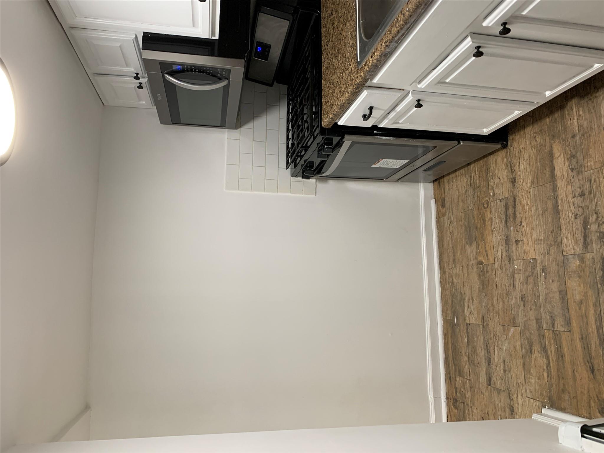 2263 Ryer Avenue Bronx, NY 10457 - Photo 46 of 49 Kitchen featuring white cabinetry, dark wood finished floors, decorative backsplash, range, and dark countertops