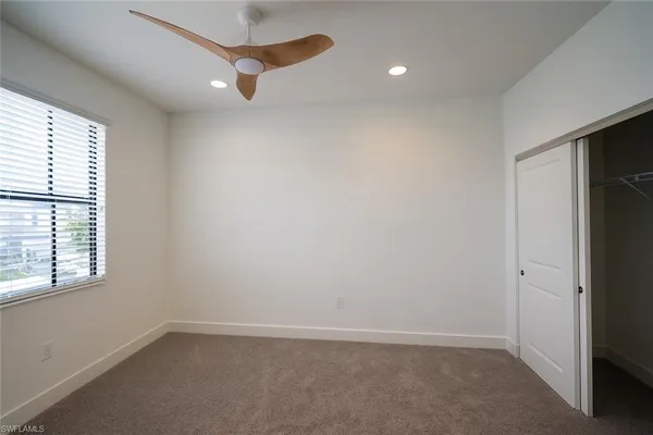 an empty room with a window and a ceiling fan