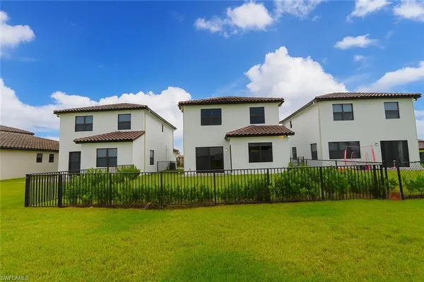 a view of a house in front of a yard with plants and large tree