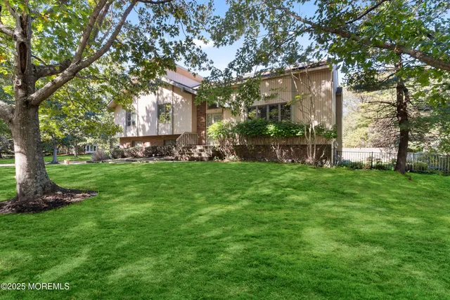 a view of a house with a big yard and large trees