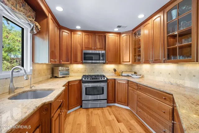 a kitchen with stainless steel appliances granite countertop a sink stove and cabinets