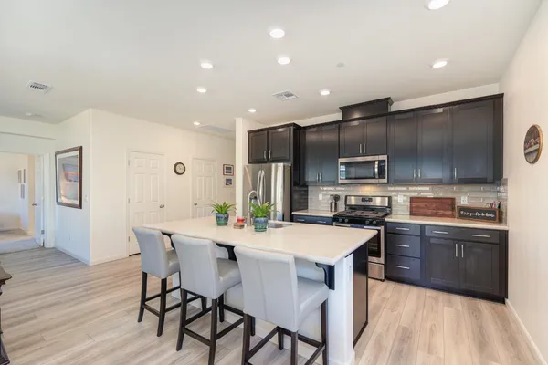 a kitchen with stainless steel appliances a sink a stove a refrigerator cabinets and wooden floor