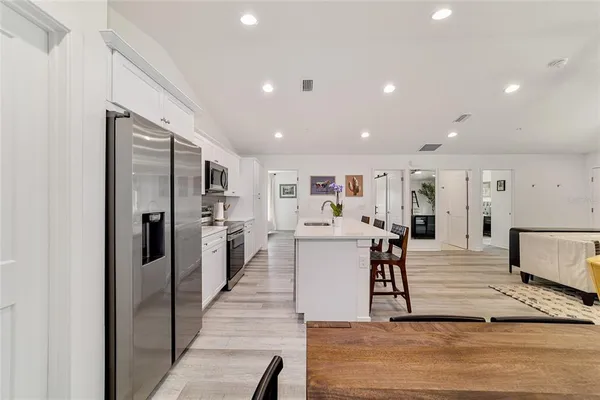 a living room with stainless steel appliances furniture refrigerator and kitchen view