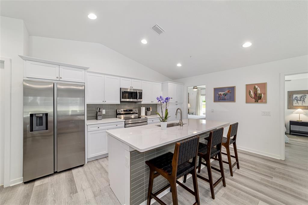 4400 Northwest 74th Terrace Ocala, FL 34482 - Photo 15 of 39 a kitchen with stainless steel appliances kitchen island granite countertop a refrigerator a stove a microwave oven a dining table and chairs with wooden floor