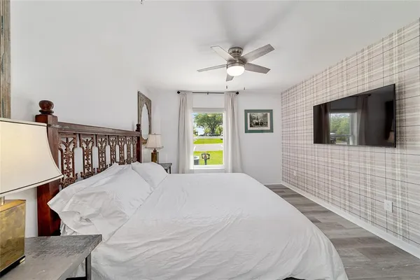 a bedroom with a bed and a flat tv screen on dresser