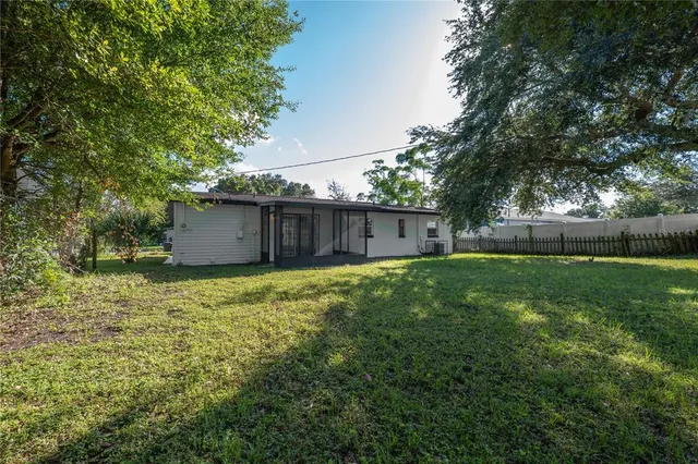 a backyard of a house with large trees and wooden fence