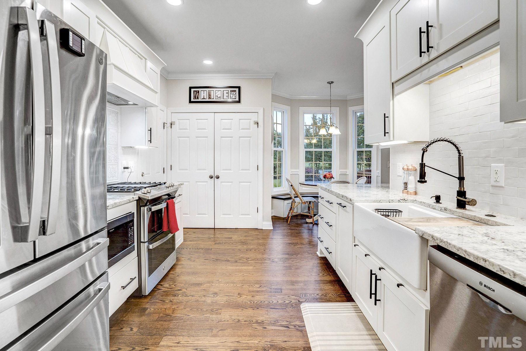 4933 Contender Drive Raleigh, NC 27603 - Photo 15 of 37 a large white kitchen with stainless steel appliances a sink and cabinets