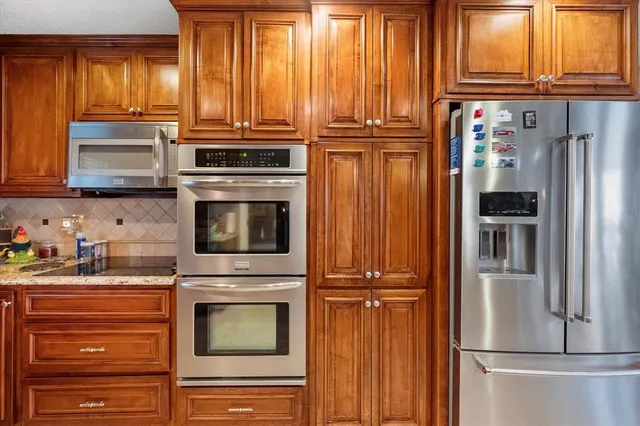 a kitchen with granite countertop a refrigerator and a stove top oven