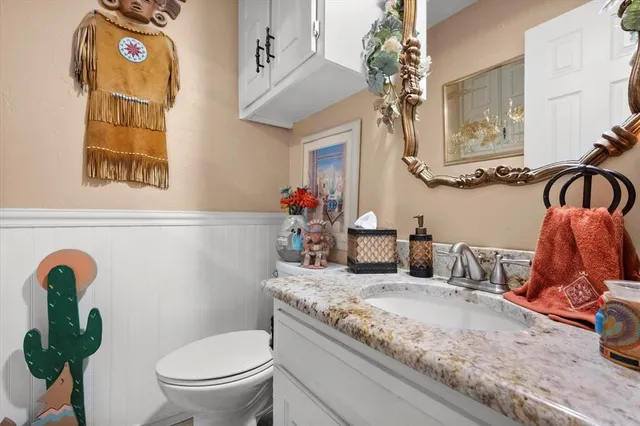 a bathroom with a granite countertop toilet sink and mirror