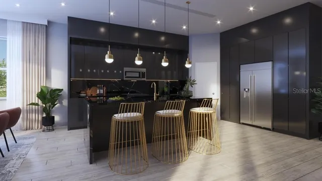 a kitchen with stainless steel appliances kitchen island granite countertop a refrigerator a oven a sink and a dining table with wooden floor