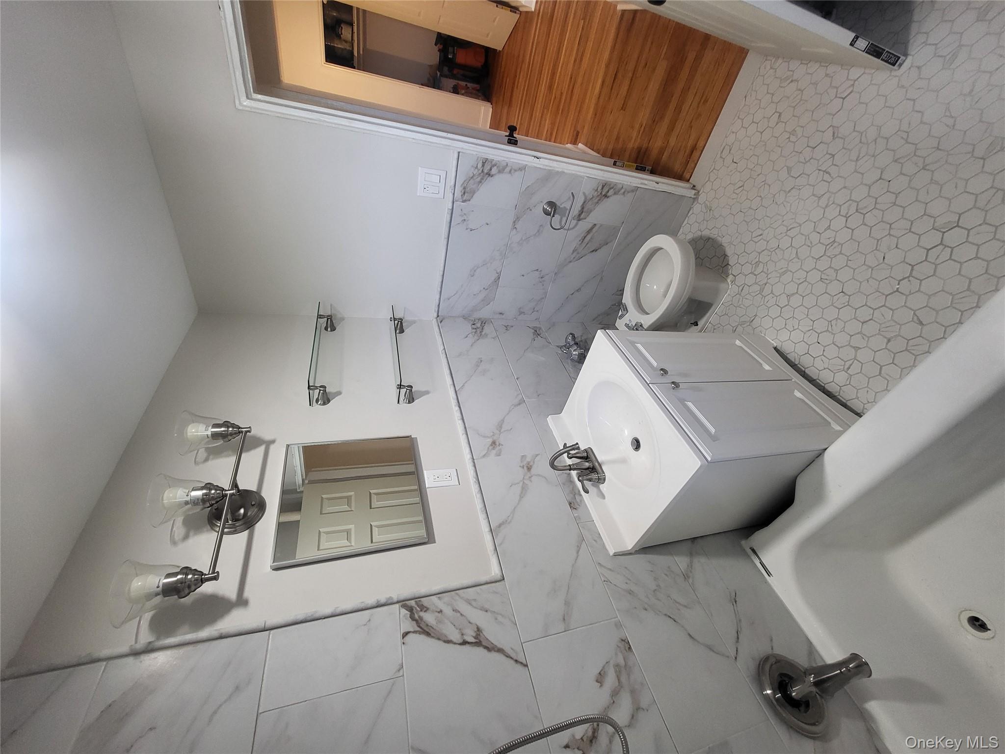 Undisclosed Address Queens, NY 11423 - Photo 14 of 22 Full bath featuring tile walls, vanity, bathing tub / shower combination, a bidet, and wainscoting