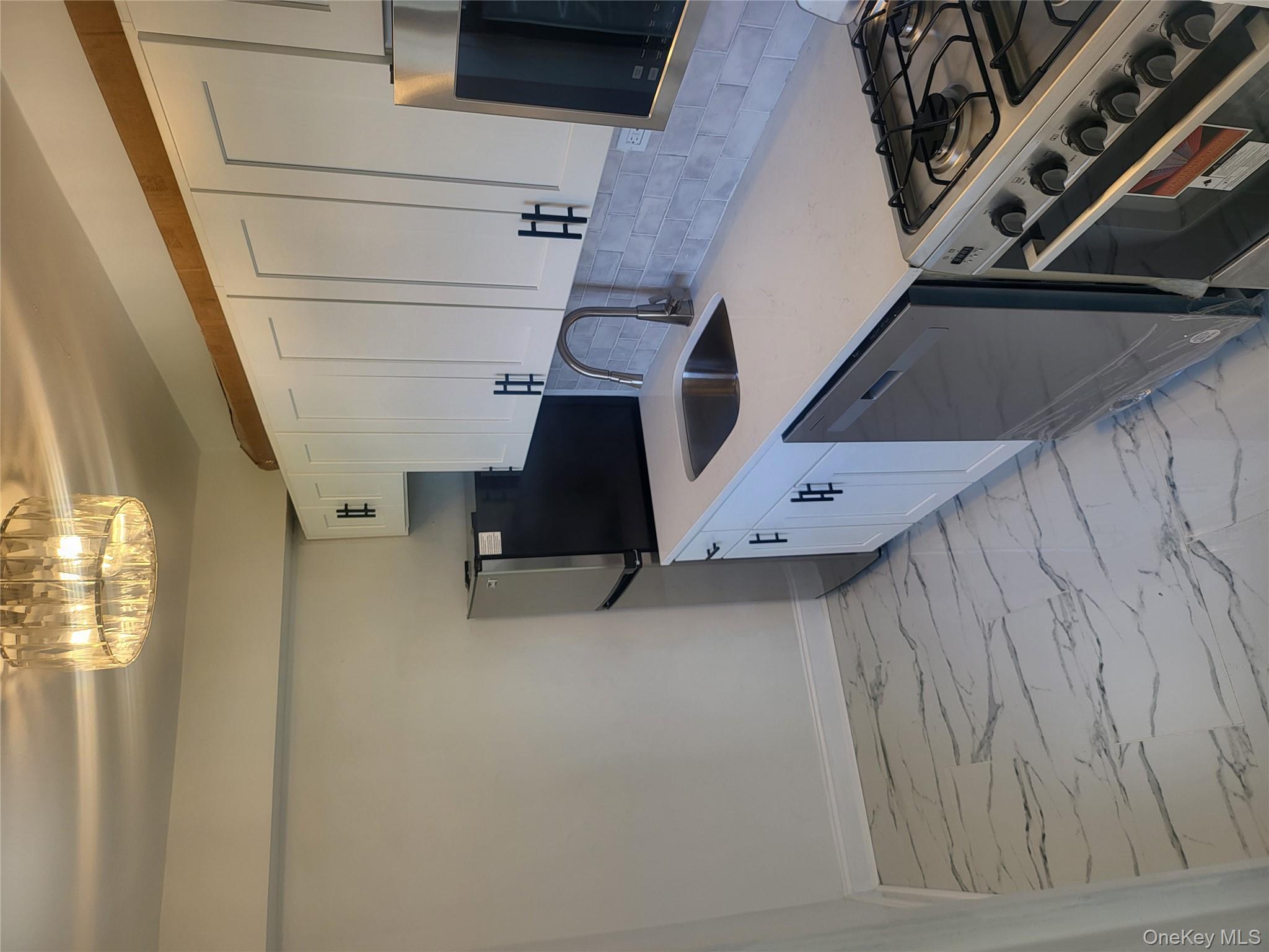 Undisclosed Address Queens, NY 11423 - Photo 2 of 22 Kitchen featuring range, white cabinetry, light stone countertops, and dishwasher