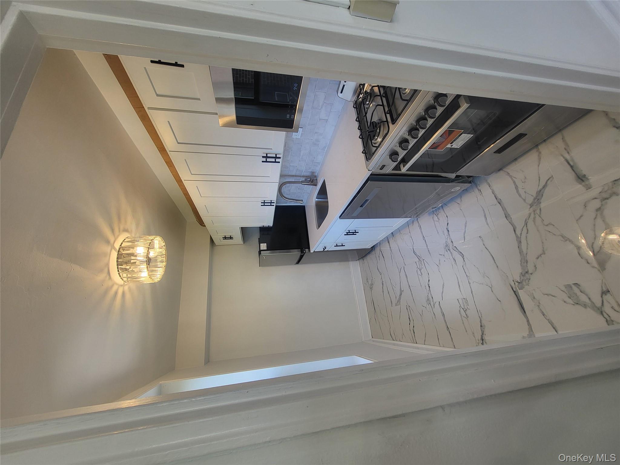 Undisclosed Address Queens, NY 11423 - Photo 3 of 22 Kitchen featuring white cabinets, range, a chandelier, light marble finish flooring, and backsplash