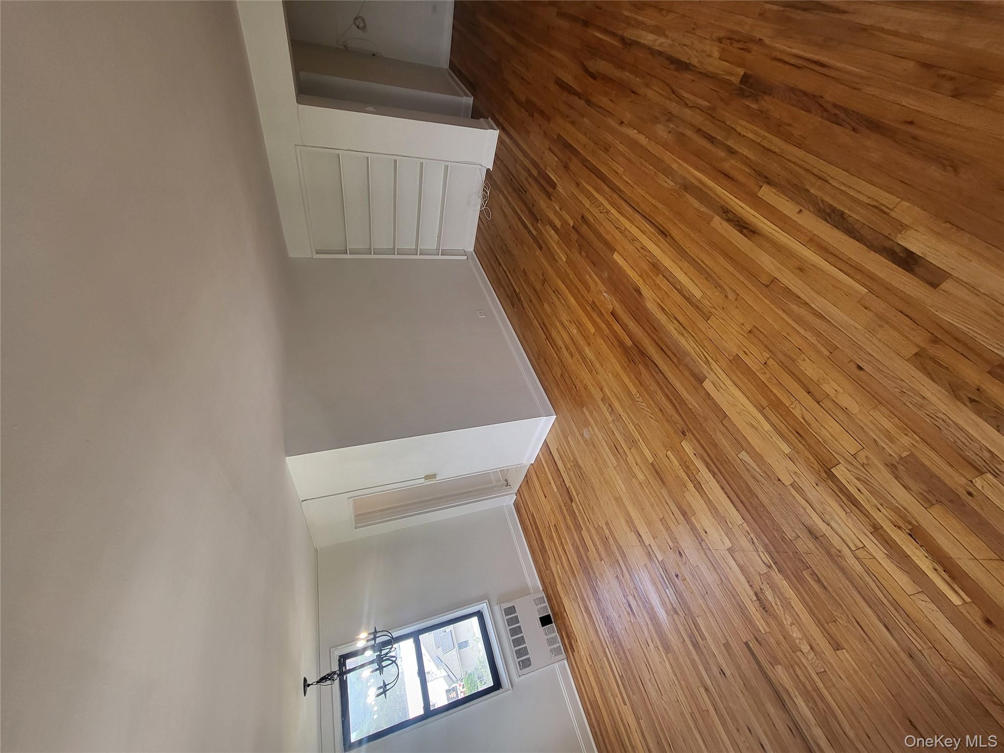 Undisclosed Address Queens, NY 11423 - Photo 8 of 22 Unfurnished living room with light wood-type flooring, a chandelier, and radiator heating unit