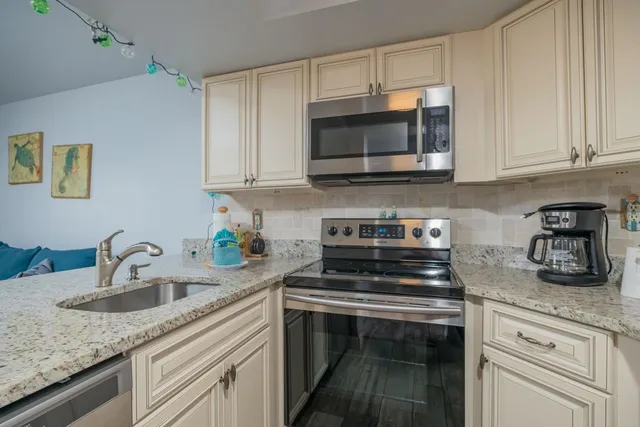 a kitchen with stainless steel appliances granite countertop white cabinets a stove a sink and dishwasher