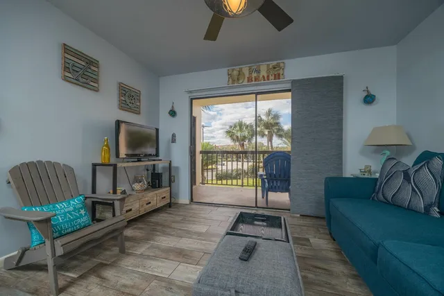 a living room with furniture a flat screen tv and a floor to ceiling window